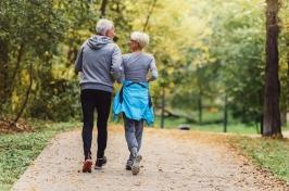 A man and a woman, shot from behind, walk along a path.